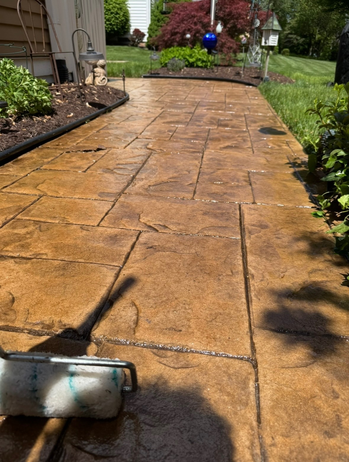 A real stamped concrete walkway being sealed with a roller.